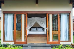 Shankara Munduk Bali في موندوك: غرفة نوم بأبواب زجاجية وسرير على شرفة