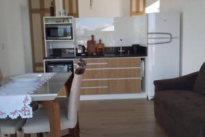 een keuken met een tafel en een witte koelkast bij Refúgio Bicho do Mar in Passo de Torres
