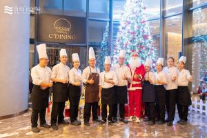 un groupe de chefs posant une photo devant un arbre de Noël dans l'établissement Khách sạn A LaCarte Hạ Long - Quảng Ninh, à Hạ Long