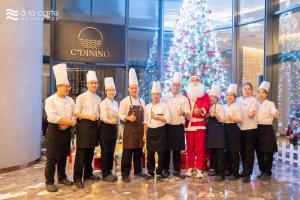 a group of chefs posing for a picture in front of a christmas tree at Khách sạn A LaCarte Hạ Long - Quảng Ninh in Ha Long