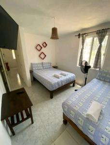 a bedroom with two beds and a table and a tv at Casa de las Palmas in Zihuatanejo