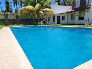 a swimming pool with blue water in front of a house at Casa de las Palmas in Zihuatanejo