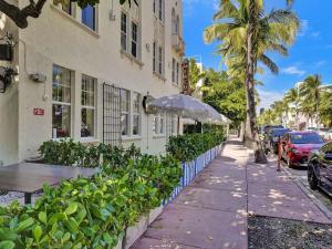 um passeio ao lado de um edifício com mesas e árvores em Park Place South of Fifth em Miami Beach