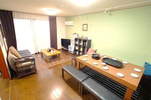 ein Wohnzimmer mit einem Tisch und einem Sofa in der Unterkunft Takamatsu Guest House Akane in Takamatsu