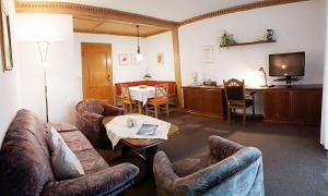 a living room with couches and a table and a television at Ferienwohnung-Susanne-im-Gaestehaus-Bergfrieden in Bad Bayersoien