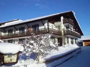 ein schneebedecktes Gebäude mit einem Baum davor in der Unterkunft Ferienwohnung Panorama im Gästehaus Bergfrieden in Bayersoien