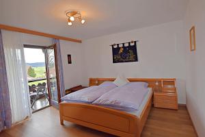 ein Schlafzimmer mit einem Bett und einem Balkon in der Unterkunft Ferienwohnung Panorama im Gästehaus Bergfrieden in Bayersoien