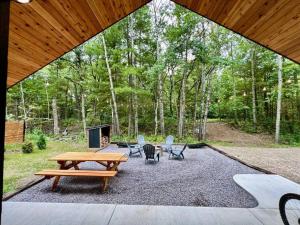 a patio with a picnic table and chairs in the woods at Cuyuna Adventure Cabin: Solo Stove - On Bike Trail in Crosby