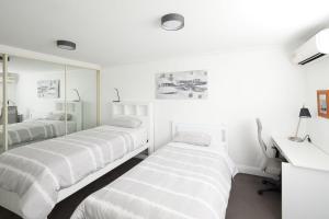 2 camas en una habitación blanca con espejo en Beach Vibe at Terrigal- Stay FOR 3 PAY FOR 2, en Terrigal