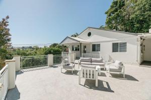 a patio with white furniture in front of a white house at Beach Vibe at Terrigal in Terrigal