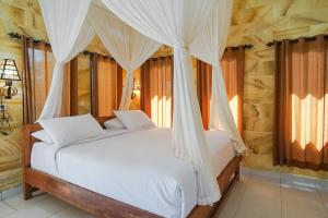 a bedroom with a bed with white drapes at Mejan Home Stay in Balian