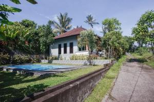 a villa with a swimming pool in front of a house at Mejan Home Stay in Balian