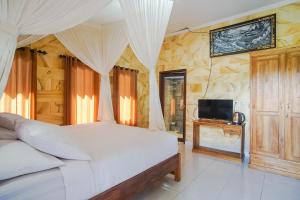 a bedroom with a white bed and a television at Mejan Home Stay in Balian