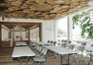 a room with white tables and chairs and a ceiling at Naya Matahora Island Resort in Longga