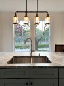 a kitchen counter with a sink and lights above it at The Blueberry House - Spacious, Family & Pet-Friendly Retreat near Sebago Lake in North Sebago