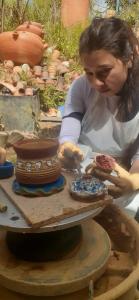 Une femme qui fait un vase sur une table dans l'établissement villa saturia, à Ráquira