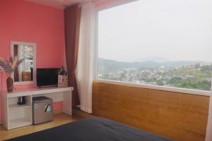 um quarto com uma grande janela e uma secretária com uma televisão em KND Golden Hills Phúc Đà Lạt em Da Lat