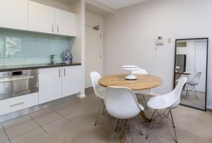 cocina con mesa de madera y sillas blancas en Domain 27 Apartment - Barton, en Kingston 