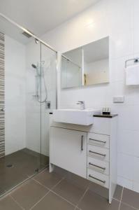 y baño blanco con lavabo y ducha. en Domain 27 Apartment - Barton, en Kingston 
