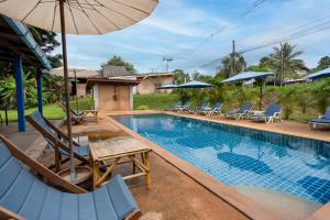 a swimming pool with chairs and an umbrella next to it at Mook Lanta Eco Resort in Ko Lanta