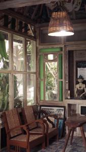 a room with chairs and a table and windows at Budarno Homestay in Yogyakarta