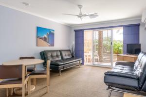 Rainbow Sands Resort في رينبو بيتش: غرفة معيشة بأثاث جلدي وطاولة