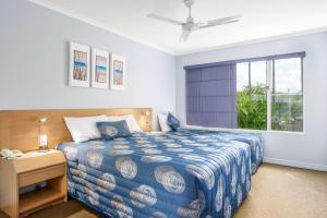 una camera da letto con un letto con un piumone blu e una finestra di Rainbow Sands Resort a Rainbow Beach