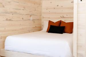 una camera da letto con un letto bianco e pareti in legno di *Tiny House Luxury Getaway: Solo Stove, Adventure* 