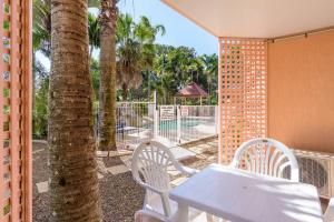 Rainbow Sands Resort في رينبو بيتش: طاولة بيضاء وكراسي على شرفة مع أشجار النخيل