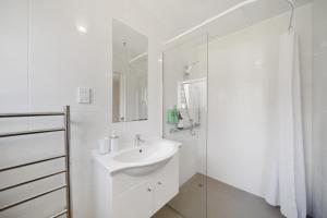 a white bathroom with a sink and a shower at Apartment 1 in Auckland