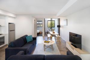 een woonkamer met een blauwe bank en een tv bij Veriu Camperdown in Sydney