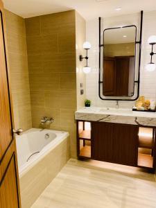 a bathroom with a tub and a sink and a mirror at Dor-Shada Resort By The Sea in Na Jomtien