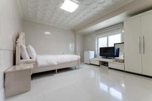 SongjuにあるHotel Gayaの白いベッドルーム(ベッド1台、テレビ付)