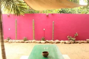 uma mesa em frente a uma parede rosa em Mi Puerto Beach Hostel em Puerto Escondido