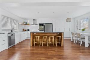 a kitchen with white cabinets and a table with chairs at Shoal Heaven in Shoalhaven Heads