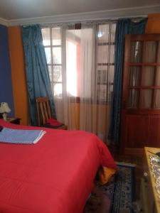 a bedroom with a red bed and a window at Casa Ballesteros Rodríguez in Oruro