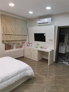 a bedroom with a bed and a desk and a tv at Marina Town in Sohar