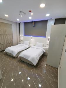 Marina Town في صحار: سريرين في غرفة ذات أغطية بيضاء
