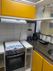 a small kitchen with a stove and yellow cabinets at EDIFÍCIO METROPOLE ONDINA in Salvador
