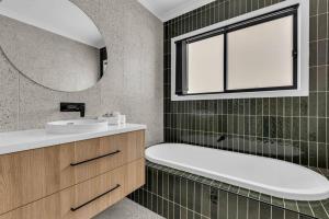 a bathroom with a tub and a sink and a mirror at Heather Merimbula in Merimbula +18 photos