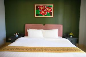 ein Bett mit einem rosa Kopfteil in einem grünen Schlafzimmer in der Unterkunft The Corner in Patong Beach