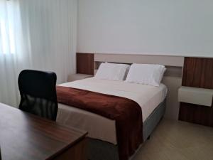 1 dormitorio con 1 cama con escritorio y silla en Residencial 04 Monte Carlo em São Roque, en São Roque