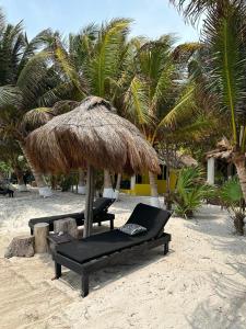 two lounge chairs under a straw umbrella on the beach at Hotel Maya Luna Adults Only in Mahahual