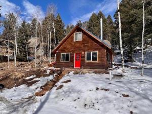 una piccola cabina con una porta rossa nella neve di Red Door cabins a Florissant