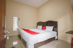 a bedroom with a large white bed with red pillows at RedDoorz near UBL Lampung 2 in Kedaton