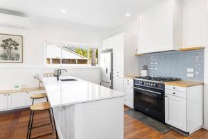 a kitchen with white cabinets and a black stove at Fairbairn Family Beach Bungalow in Busselton