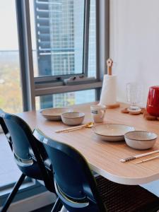 une table en bois avec des bols et des chaises autour de celle-ci dans l'établissement Share House Master Room Near Chatswood Station, à Sydney