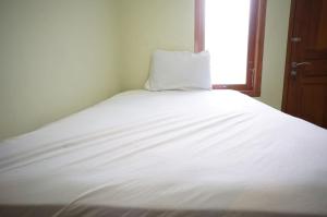 a white bed in a room with a window at Spot On 93382 Gajayana Kost Female Only Syariah in Jenggrik