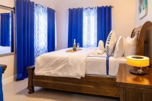 a bedroom with a bed with blue curtains at Welcome to our Ocean View Villa! in Lucea