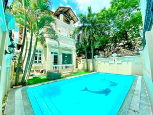 a swimming pool in front of a house with palm trees at Gem villa 1915-16 phòng ngủ-2 hồ bơi lớn in Ho Chi Minh City